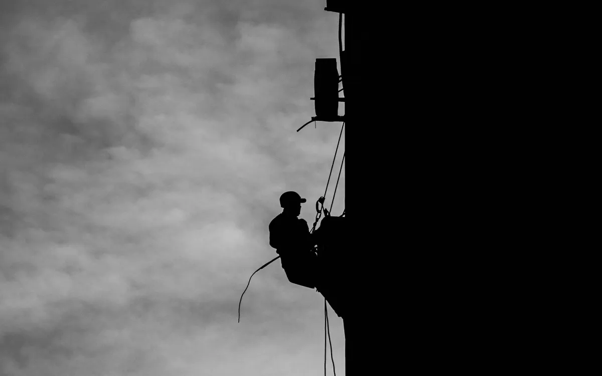 Trabajador asegurado con arnés y cuerdas en una estructura elevada
